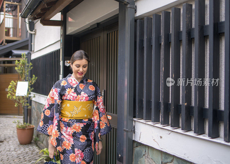 穿着和服的白人妇女走在传统的日本狭窄的小路上