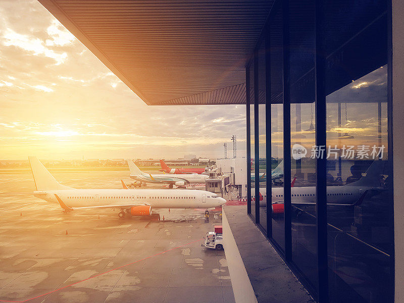 飞机在机场终点站门口，现代国际机场日落时分。乘飞机运输和旅行的概念