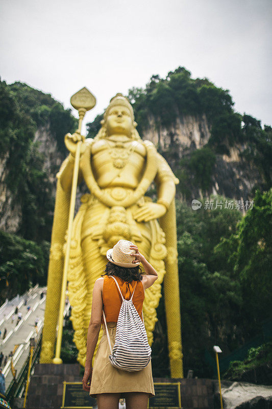 年轻女子站在Murugan雕像前