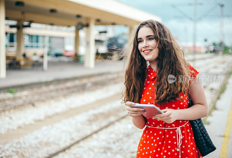 一位穿着红衣服的女旅客站在火车站上