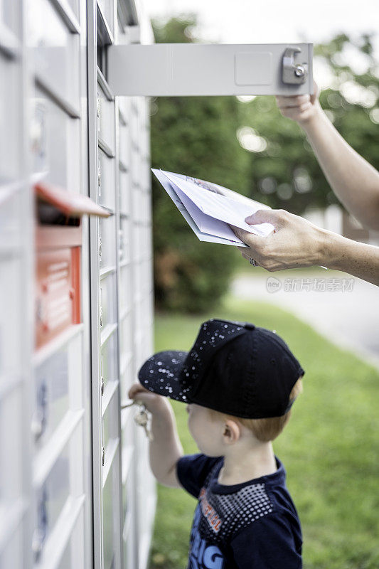 一个女人和一个小男孩在邮筒里拿邮件