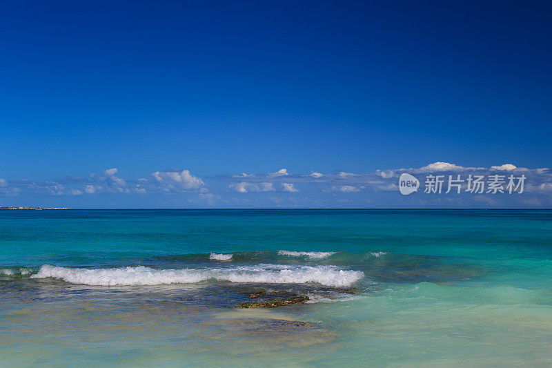 加勒比海与海浪打破海岸，蓝色和蓝绿色的水和蓝色的天空，坎昆，墨西哥。