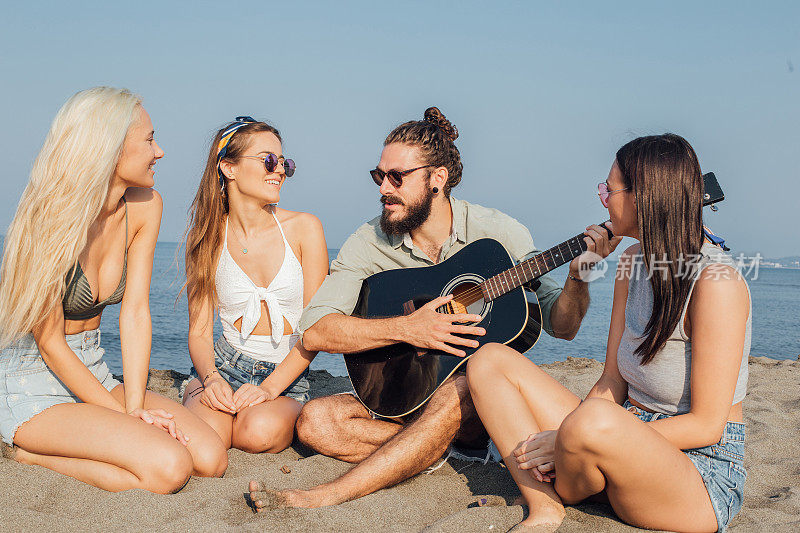 四个朋友在海滩上弹吉他