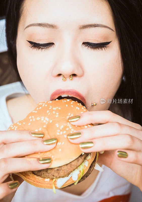年轻的亚洲女人在吃汉堡包