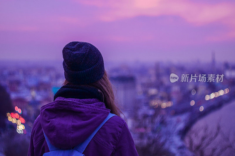 游客潮人看着冬天的城市夜景和紫色的天空