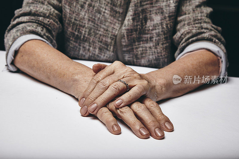 老妇人的手搁在灰色的表面上