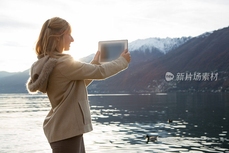 年轻女子在湖边用数码平板电脑winter拍照