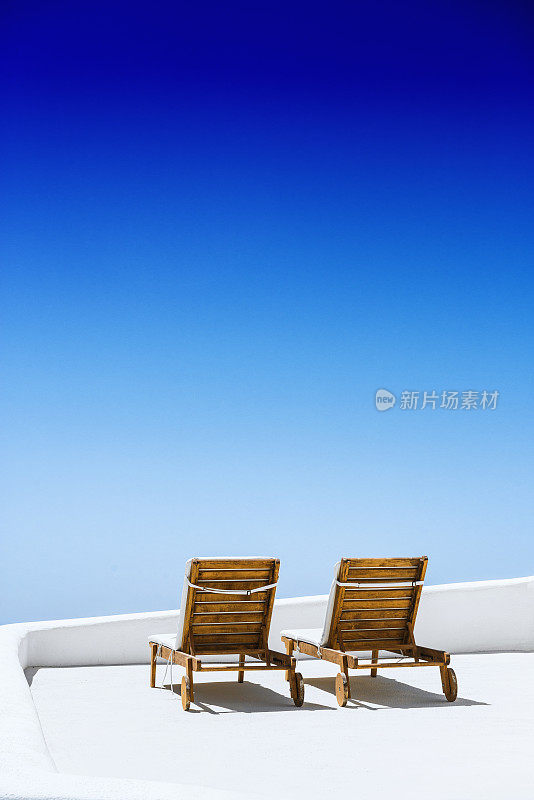 日出时分，圣托里尼岛阳台上的空太阳躺椅