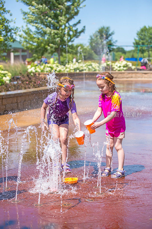 两个女孩在喷泉里玩塑料杯