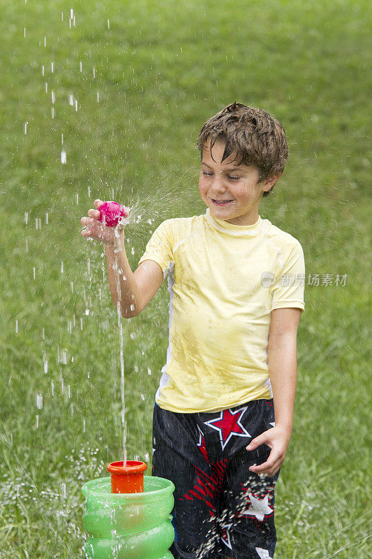 小男孩在院子里玩喷泉玩具和球