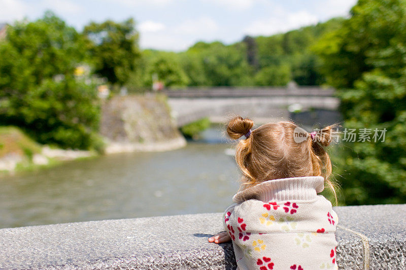 年轻的金发女郎站在桥上，欣赏着眼前的风景