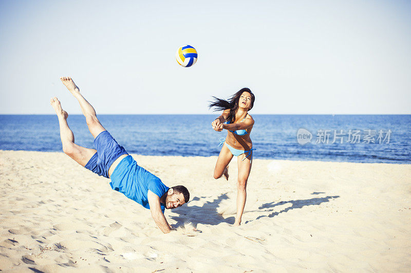 一对年轻夫妇在沙滩上打排球