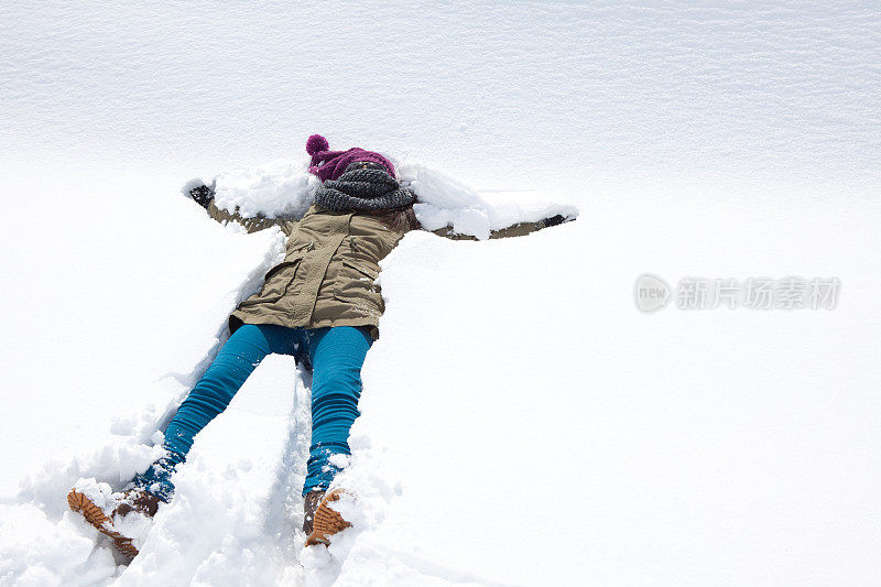 快乐的年轻女子躺在雪地上