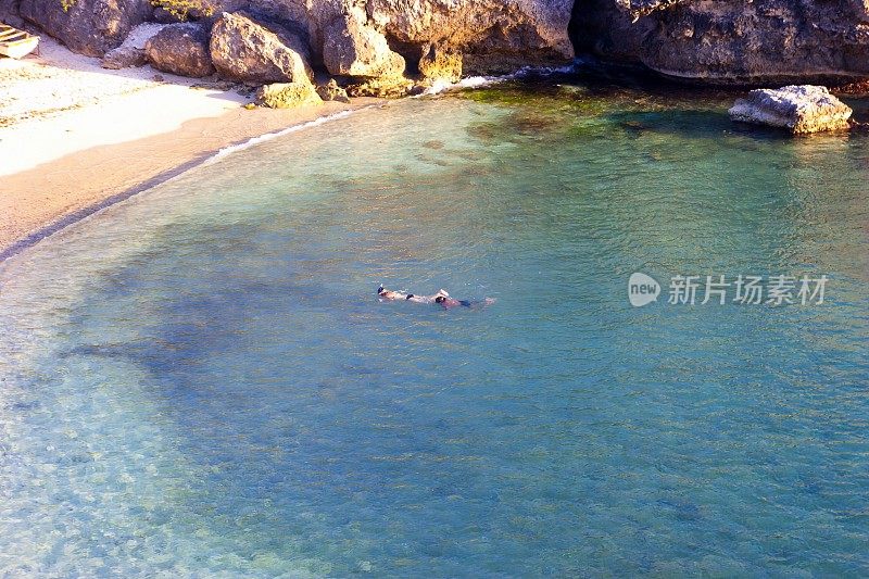 年轻的夫妇浮潜在海湾与绿松石水