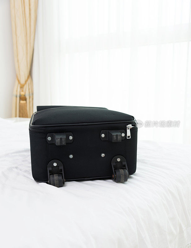 单只黑色行李箱放在酒店床上