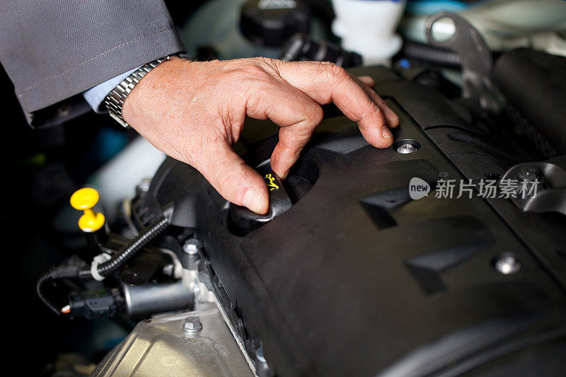 在汽车修理厂…汽车修理工正在检查机油