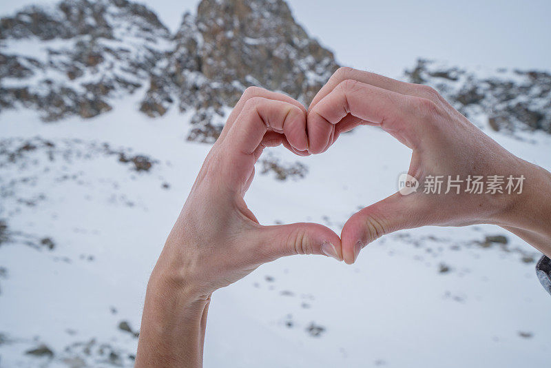 人的双手在雪山景观上做出心形