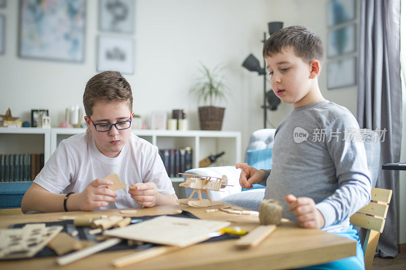 兄弟们正在为学校项目制作木制模型飞机