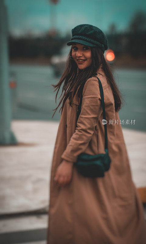 一个女人走在城市的街道上，看着镜头。年轻女子在马路上。