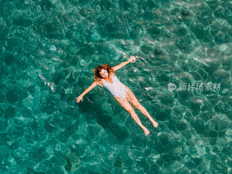 鸟瞰图女人漂浮在清澈的大海