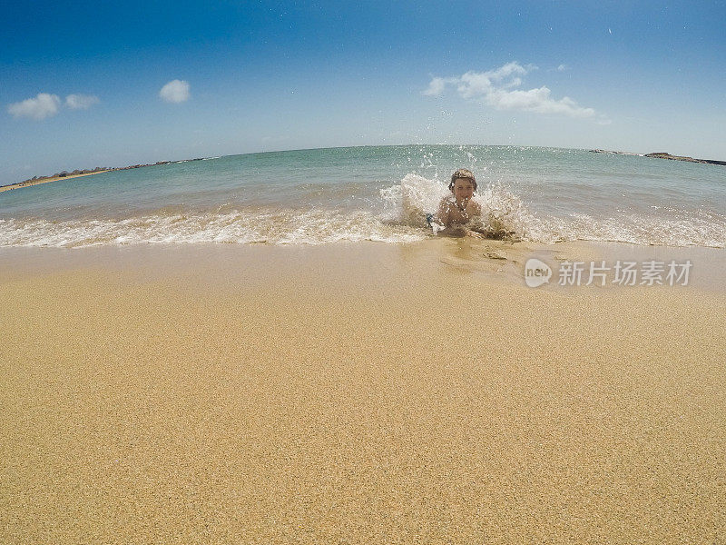 在天堂里游泳，孩子们在考艾岛的海洋里游泳，在荒芜的海滩上玩耍