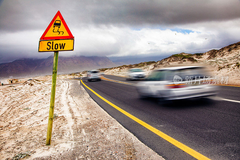 在南非滑溜溜的海滩路上，汽车超速驶过一个缓慢的标志