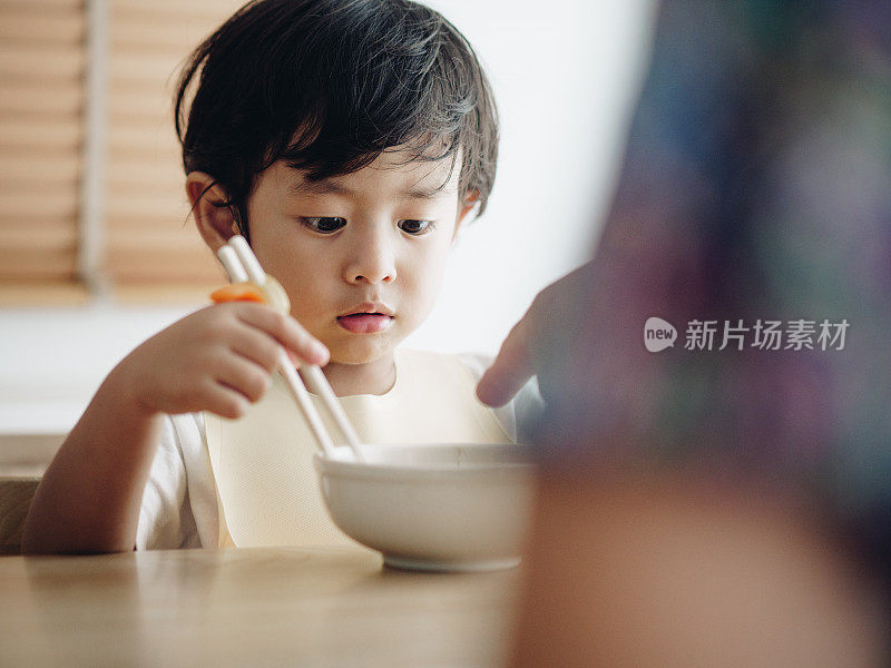 微笑的小男孩在高椅子上吃