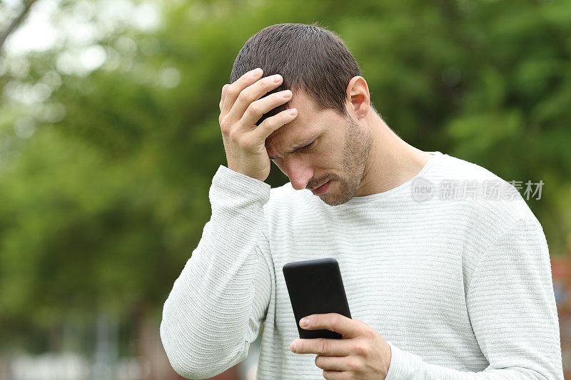 一个悲伤的成年人在公园里查看手机短信