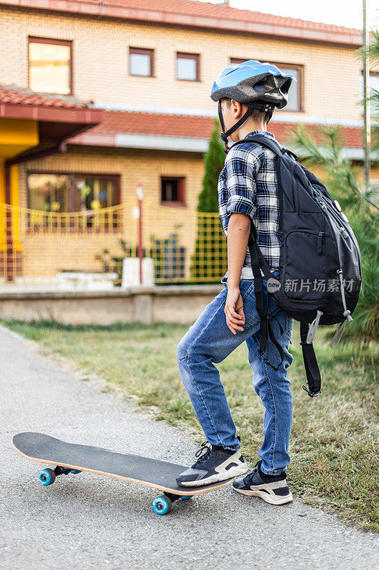 骑着滑板上小学的小男孩