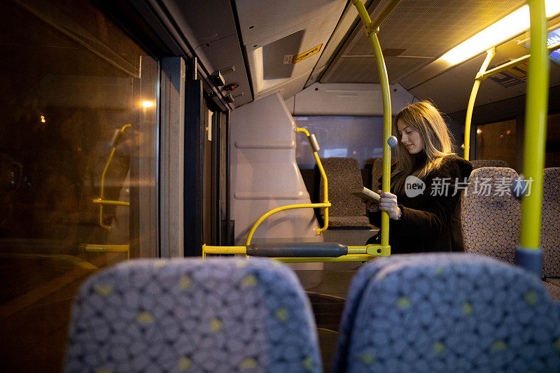 女乘客晚上乘公共汽车时看书。晚上，女孩在一辆行驶的车上读故事