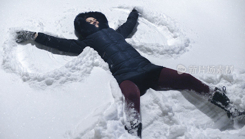 一个在冬季度假胜地做雪天使的女人