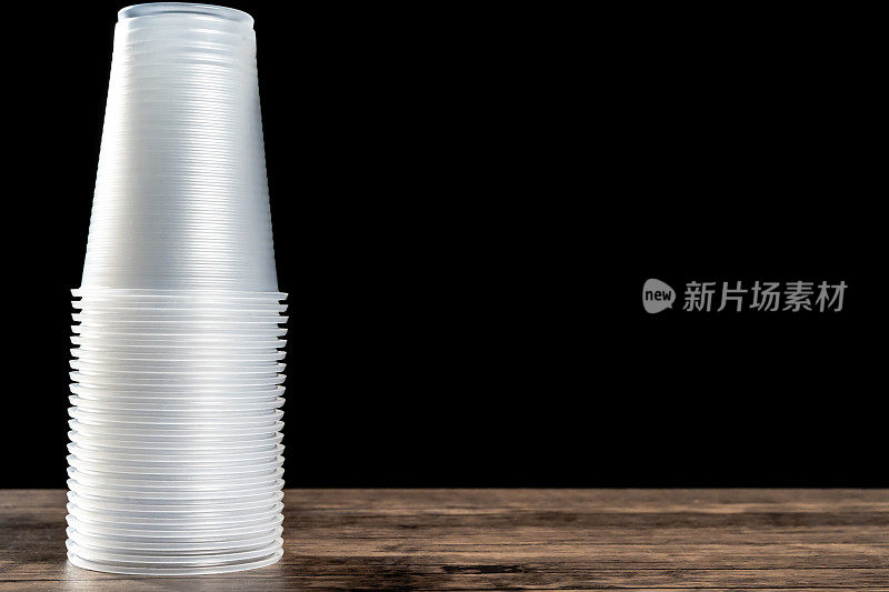 特写的塑料杯在木制桌面在前面的黑色背景