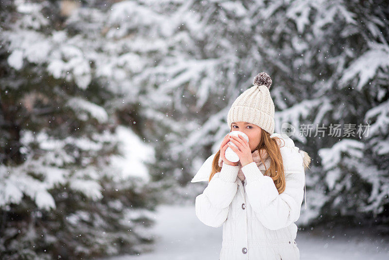 年轻女子喝着咖啡，热巧克力，茶，外面是雪