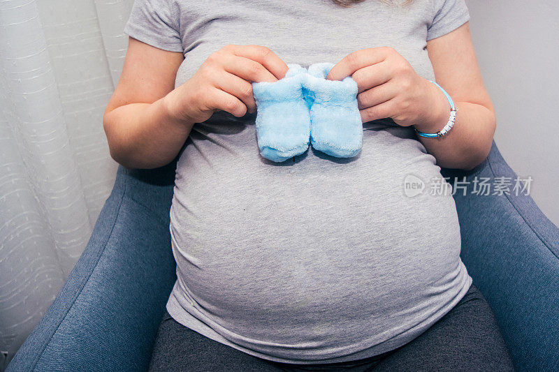 孕妇的肚子与新生婴儿的靴子库存照片