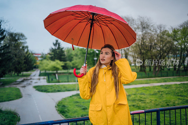 穿黄色雨衣带伞的女人