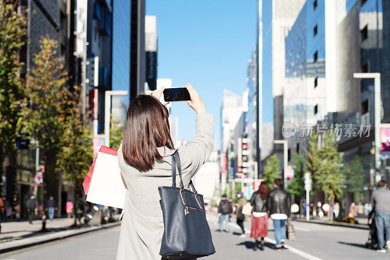 后视图的女人与购物袋拍照的城市景观