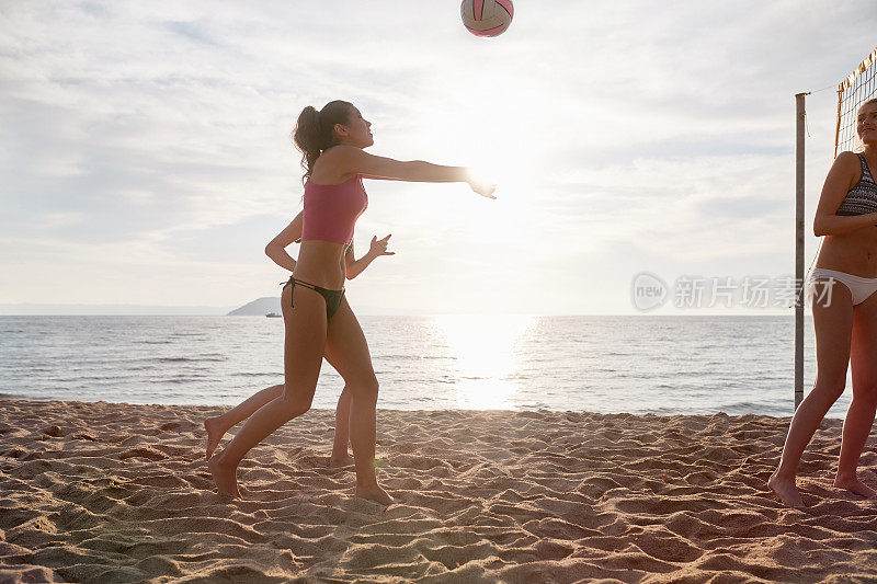 年轻女子玩沙滩排球等着挖球
