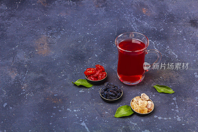 在土耳其茶杯(armudu)中加入东方风格的山茱萸、葡萄干和糖，在深色背景上饮用红茶(rooibos，芙蓉，karkade)。草药，维他命，排毒茶治疗感冒和流感。文本复制空间