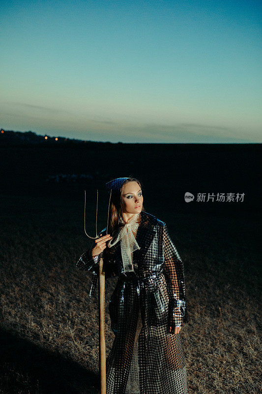夜里，农妇拿着干草叉站在田间。