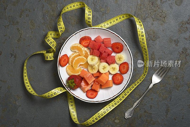 用卷尺测量早餐的新鲜水果片。