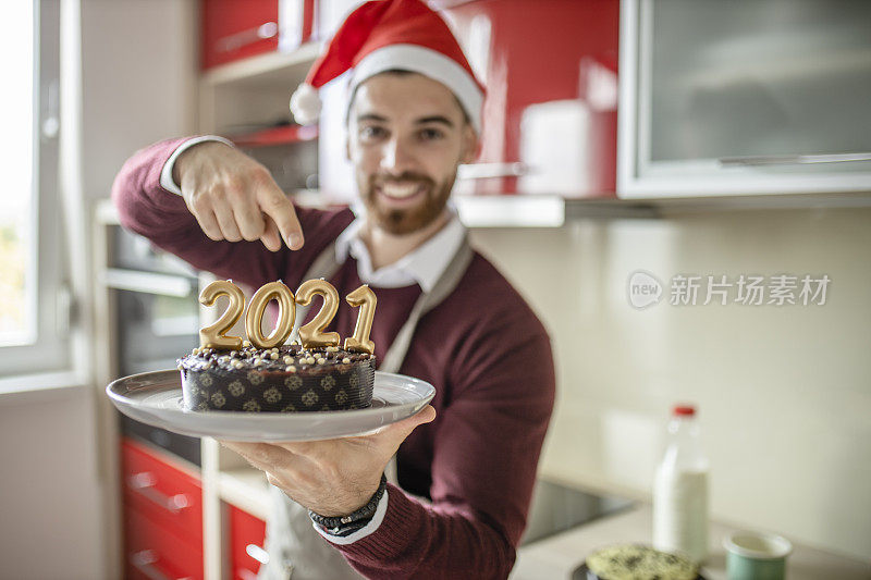 特写的年轻人正在准备新年晚餐在他的家的厨房。他正在准备巧克力蛋糕当甜点