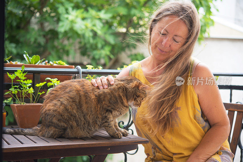 阳台上的长头发老妇人和她的虎斑猫