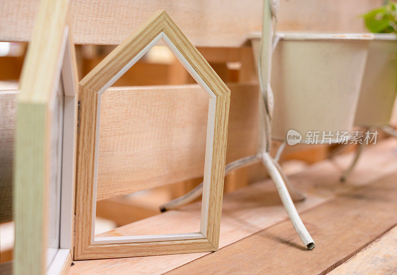 木桌上木质相框的特写和选择性聚焦拍摄，花瓶里插着植物，极简的北欧风格装饰。这是一种艺术构图，为家庭内部提供复制空间。