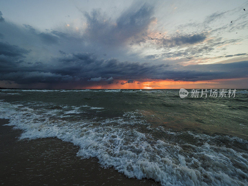 日落时，鸟儿在暴风雨的波罗的海上空飞翔