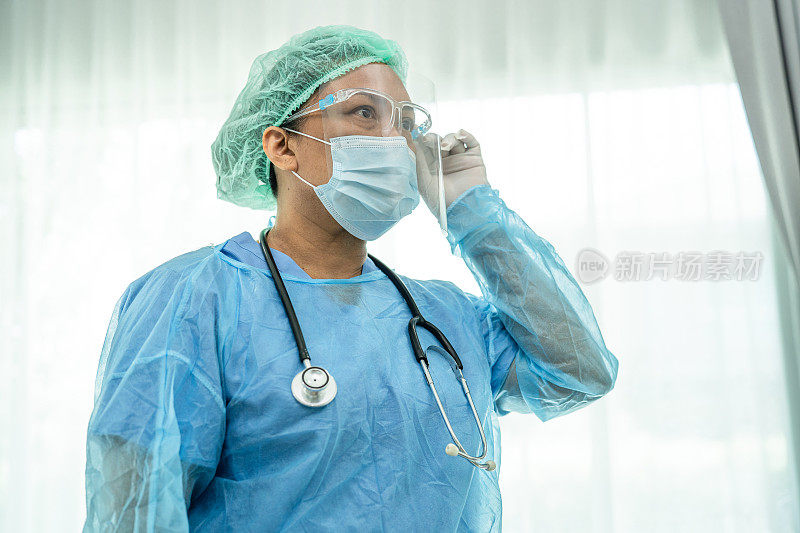 亚洲医生穿戴面罩和个人防护服检查患者防护安全新常态感染新冠肺炎疫情在隔离护理医院病房爆发。