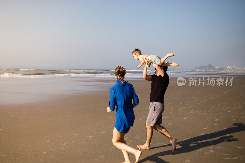 父亲把儿子举在空中，在海滩上玩耍