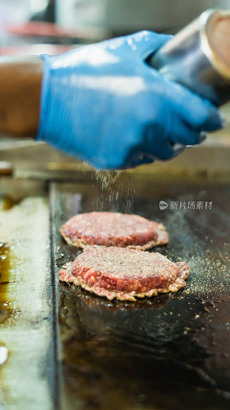 在一家餐厅的商业厨房里，一位面目全非的厨师正在准备美味的汉堡