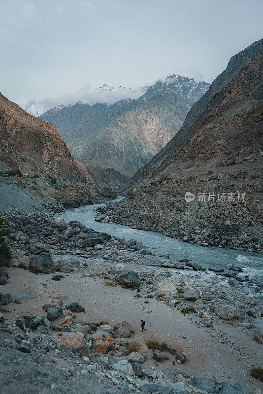 巴基斯坦北部，一名男子站在河流和山脉的背景上