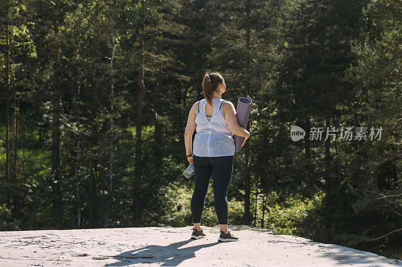 一个穿着运动服的不知名的女人在森林里寻找做瑜伽的完美地点