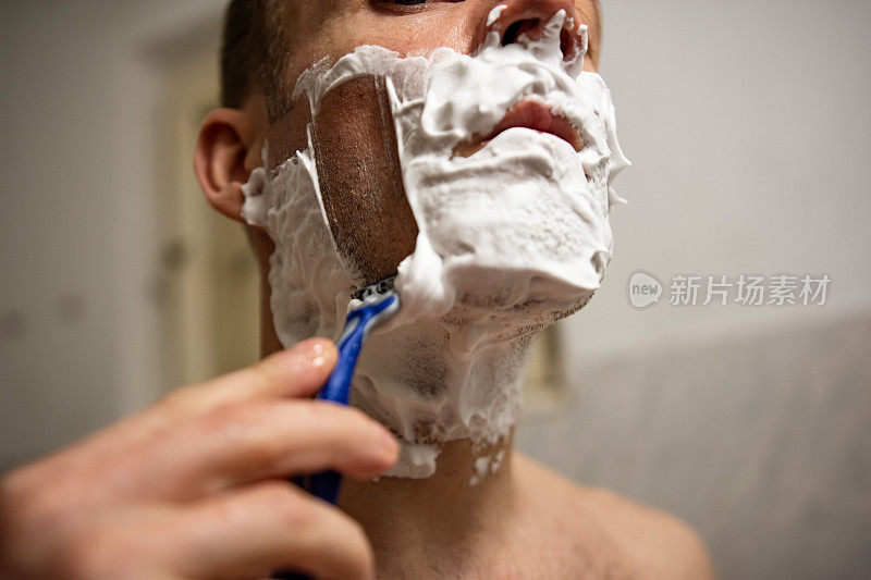 用剃须刀刮胡子的男人
